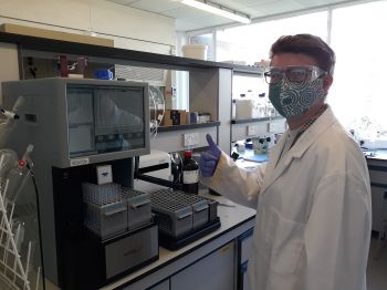 Charlie in the Chemistry lab with a face covering, giving a thumbs up