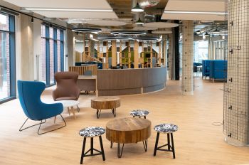 A modern space with a semi-circular reception desk, some stools and couple of armchairs around low coffee tables.