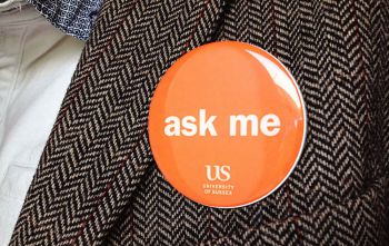 Orange Ask Me badge on tweed jacket