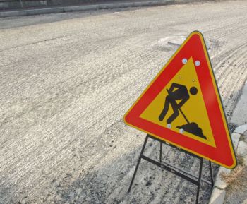 A yellow and red road sign, with an image of digging work being carried out.