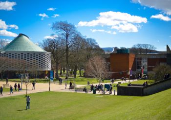 Sussex campus showing a round building with turret roof and trees surrounding it