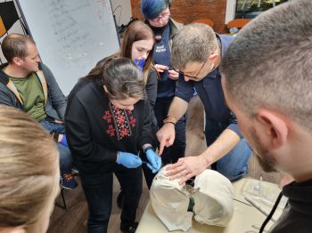 A group of BSMS students stood around a medical Phantom being made wearing blue gloves