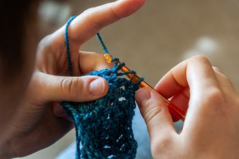 A close up shot of someone crocheting with blue yarn