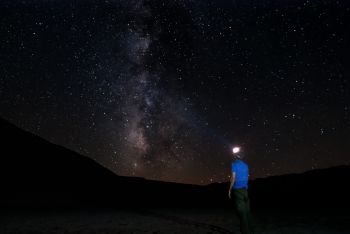 A man looks up at the stars in a night sky