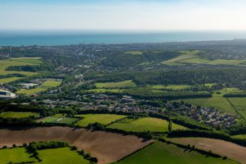 Aerial view of coastal city and green fields under clear skies