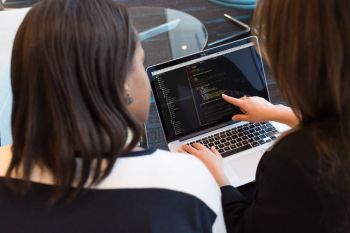 A photo of two people looking at the screen of a laptop