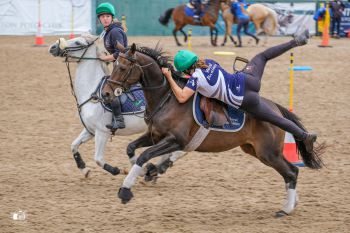 A female mounted games athlete pulling herself onto a moving horse