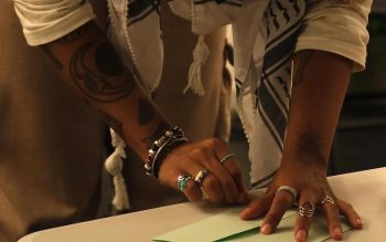 Photograph of Erin James's hands folding a piece of paper while leaning over a desk