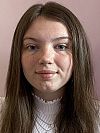 A person with long dark hair and white high neck blouse