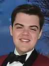 A person with dark hair smiling wearing a velvet suit and bow tie