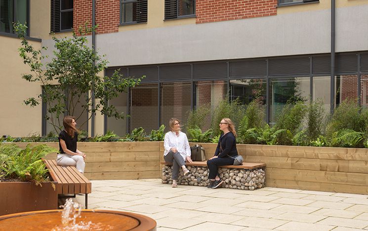 three women sitting on benches outside looking at each other