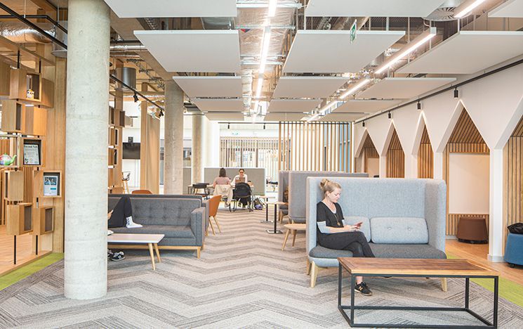 Several people sitting in the student centre on sofas and at a table