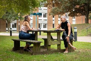 Two people sitting on a bench on campus