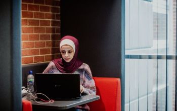 Student reading on her laptop at the Library