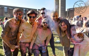 Group of students covered in colourful powder in the lawn outside Arts A