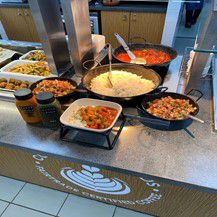 Four pots and pans with rice and chopped vegetable on a counter