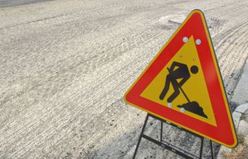 A yellow and red road sign, with an image of digging work being carried out.