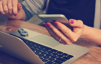 Student holding phone, next to laptop