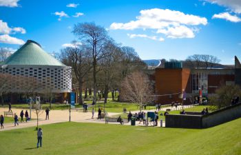 Sussex campus showing a round building with turret roof and trees surrounding it