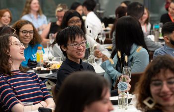 Smiling students sitting at tables enjoying themselves at the Spirit of Sussex Award celebration event