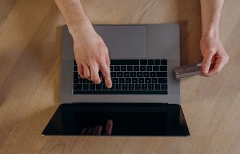 A person's hands using a laptop and holding a credit card