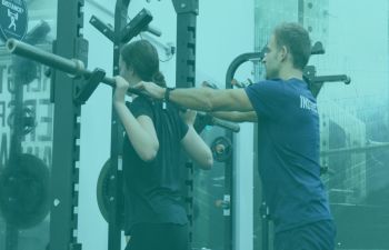 A fitness instructor assisting a woman lifting weights