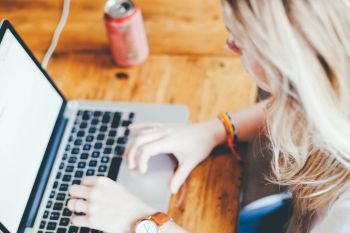 Woman working at laptop with a drink next to her