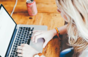 Woman working at laptop with a drink next to her