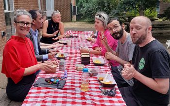 photo of people sitting at picnic table eating lunch