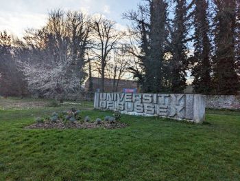 A photograph of the concrete University of Sussex sign at the entrance to campus