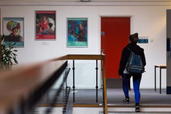 A person carrying a backpack is reaching the last step of the stairs