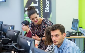 A lecturer helps students working at computers.