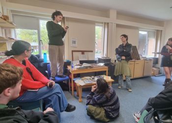 Student standing on a chair speaking to a group of students