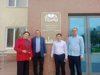 Four people stand in front of a building with a plaque showing that it is the Tashkent State Pedagogical University. Marcelo stand second in from the left.