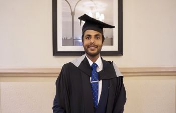 Ravi at his graduation dressed in cap and gown and smiling at the camera