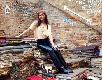 Juliahna Mistretta seated on piles of books, smiling