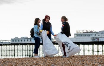 3 people stood together talking whilst on Brighton Beach for a beach clean