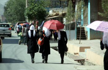 Afghan school girls walking away from camera along a road.