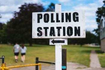 A white wooden sign post with black painted letters reading 'Polling station'