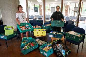 Photo of two Sussex staff members with crates full of food donations