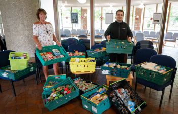 Photo of two Sussex staff members with crates full of food donations