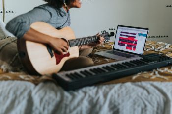 Musician playing guitar and using computer