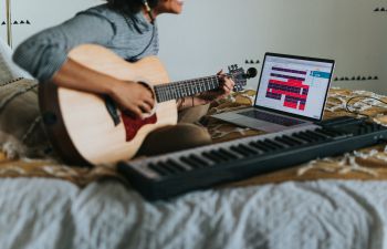 Musician playing guitar and using computer