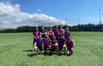 young people wearing football clothes standing together on a football pitch