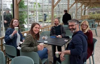 A photo of five colleagues from the School of Life Sciences around a table. Some have a cup of coffee or tea in their hands