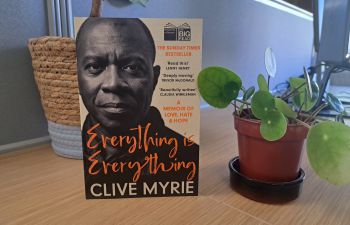 A copy of 'Everything is Everything' by Clive Myrie, propped up next to potted plants