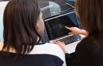 A photo of two people looking at the screen of a laptop