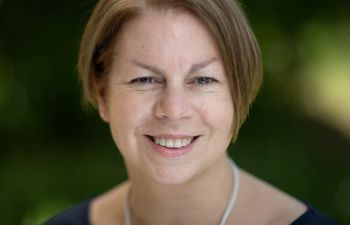 A smiling Lisa Holmes is photographed in an outdoor setting