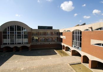 Red brick L-shaped building with archways and large glass windows