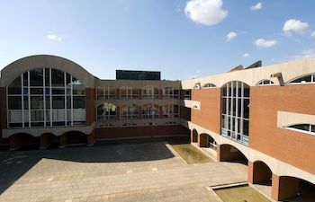 Red brick L-shaped building with archways and large glass windows